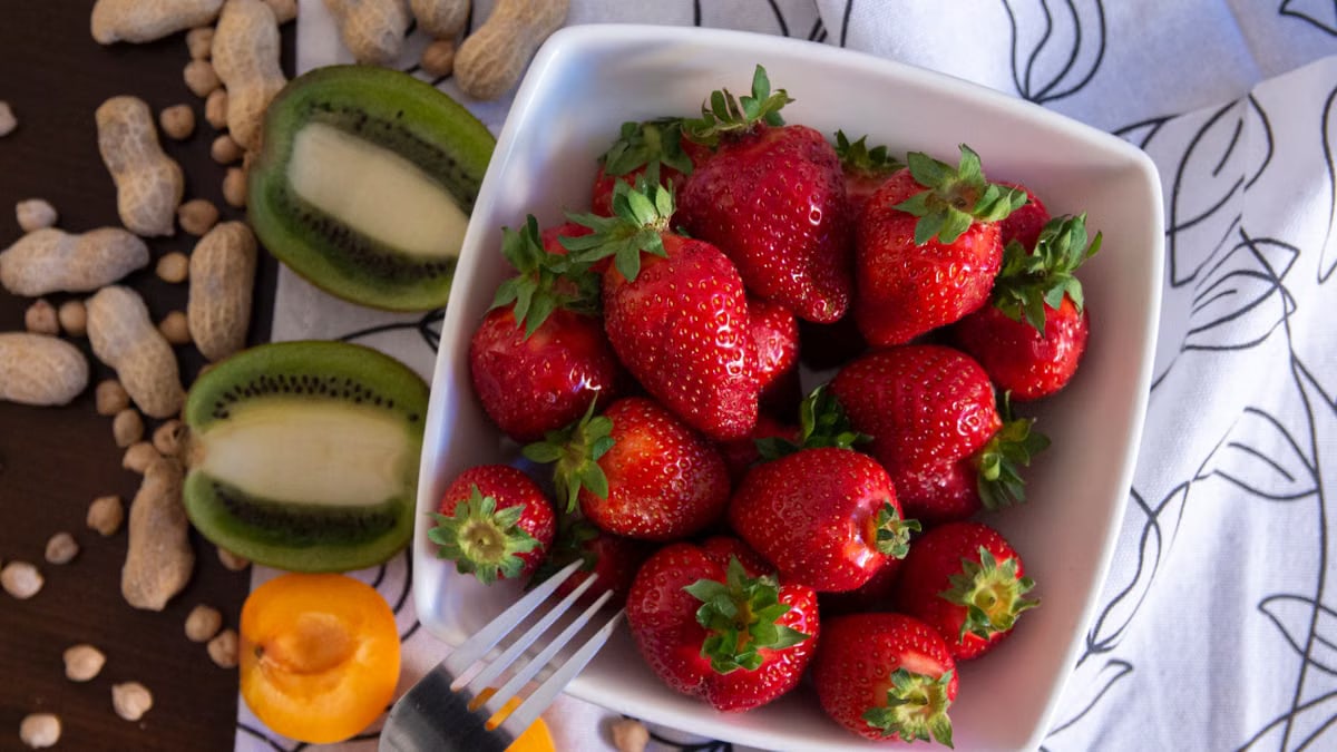 A vibrant flat lay of fresh strawberries and kiwi slices in a ceramic bowl, perfect for food photography.