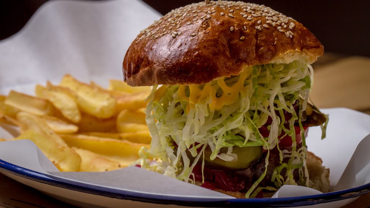 Delicious cheeseburger with lettuce and tomato, served with crispy fries on a plate.